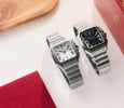 titanium and black-dial steel Cartier Santos models side by side