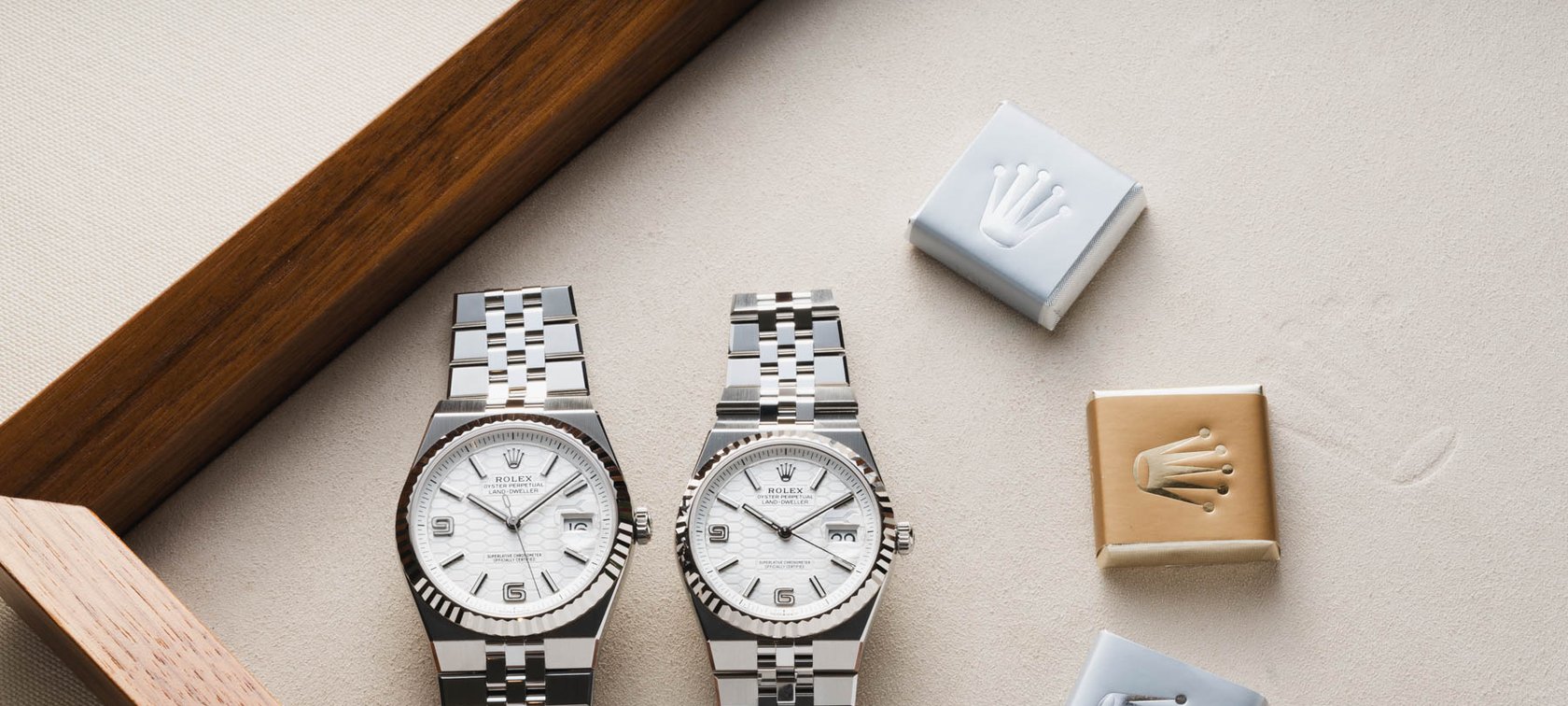40mm and 36mm steel Rolex Land-Dweller models side by side on tray with chocolates