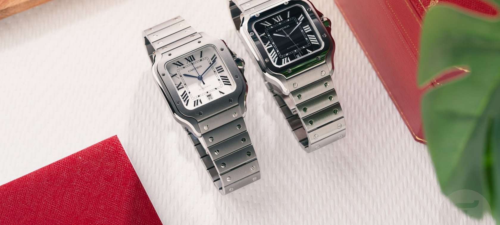 titanium and black-dial steel Cartier Santos models side by side