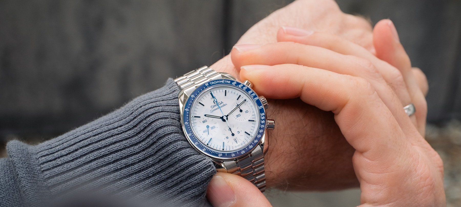 Omega Speedmaster Milano Cortina 2026 on wrist, over-should shot, finger on pusher