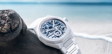 Zenith × Time+Tide Defy Skyline Skeleton White Surfer Ceramic on beach, propped up on driftwood