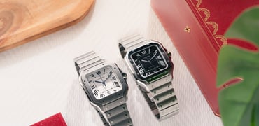 titanium and black-dial steel Cartier Santos models side by side