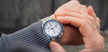 Omega Speedmaster Milano Cortina 2026 on wrist, over-should shot, finger on pusher