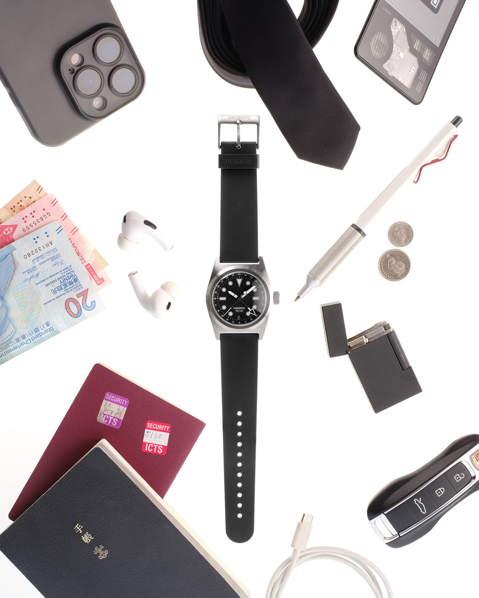 Unimatic Modello Due U2-GMT "World Timer" flat-lay with passports, keys, pen, lighter, ear buds, etc.