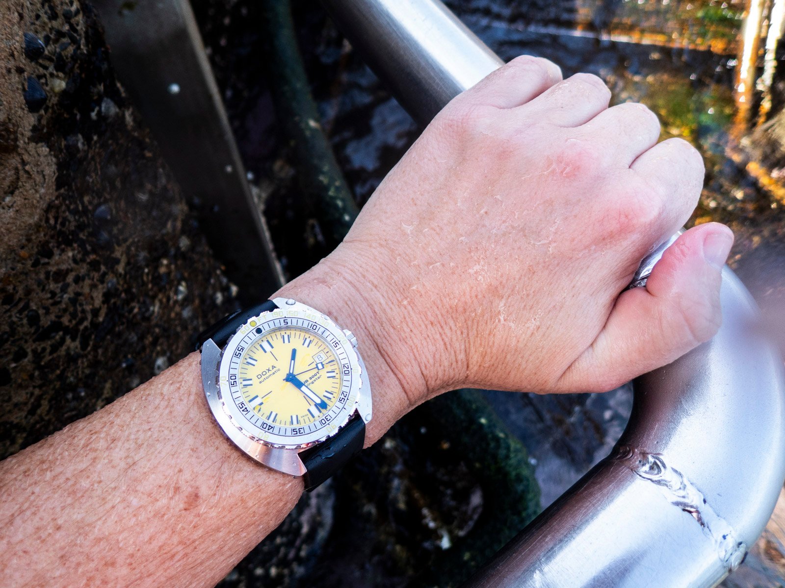 Doxa Sub 300T on wrist, holding railing