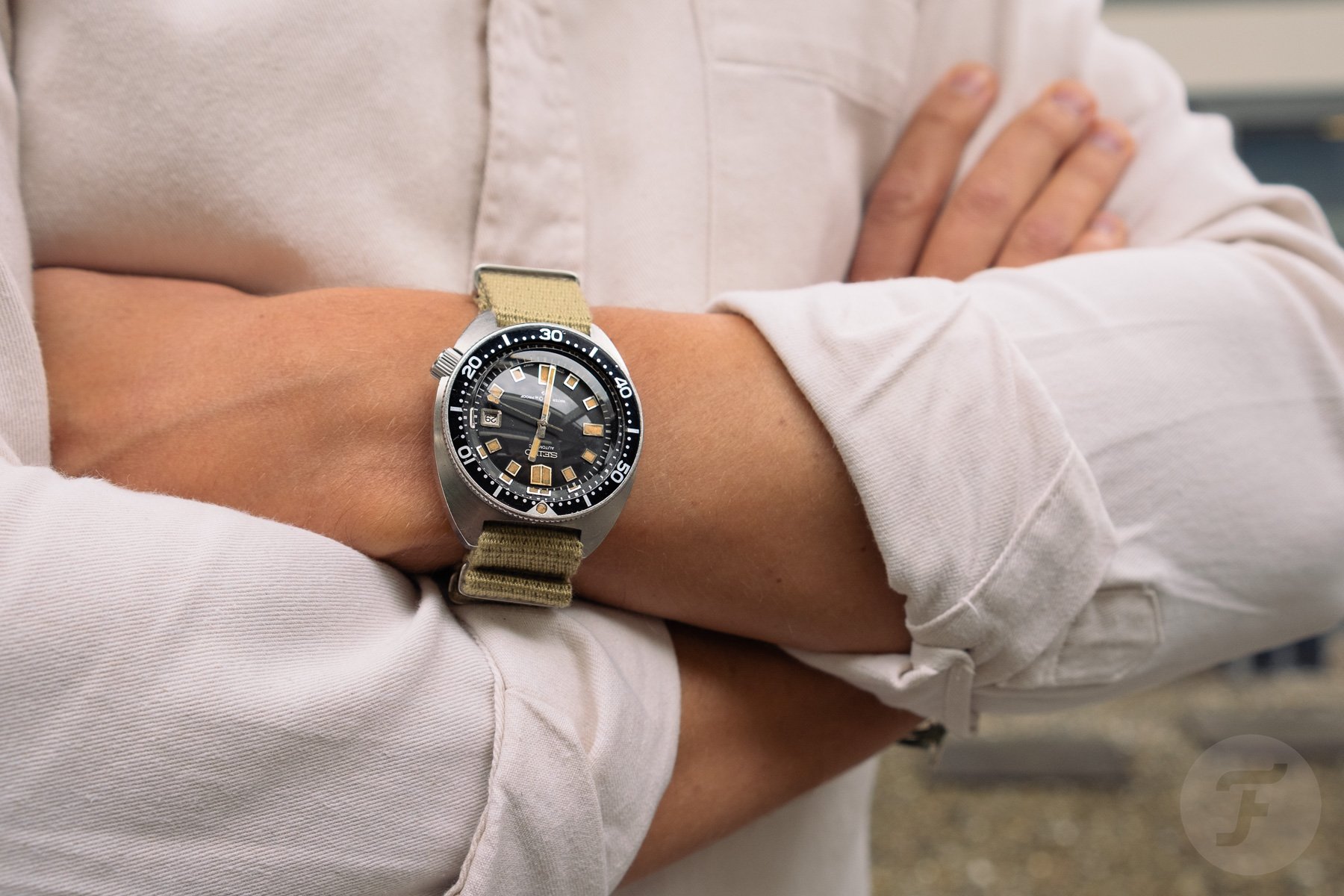 Vintage Seiko 6105-8000 with a NATO strap on wrist, arms crossed