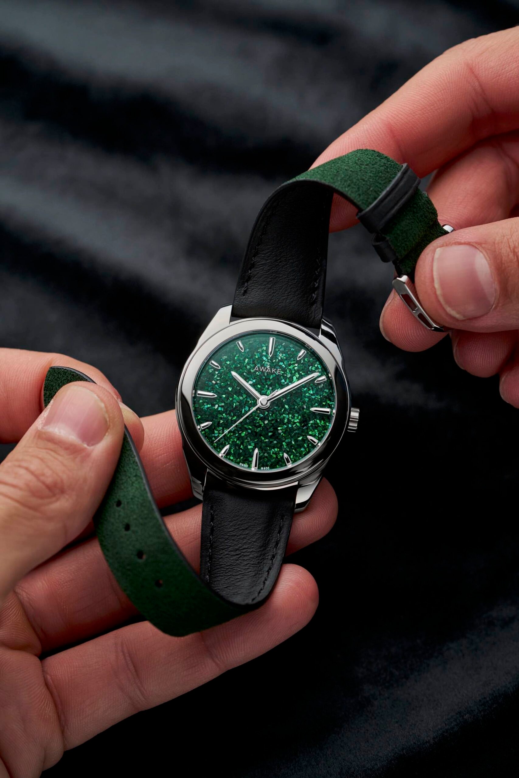Awake Sơn Mài Fragments Green in hands, flexing the strap to show lining
