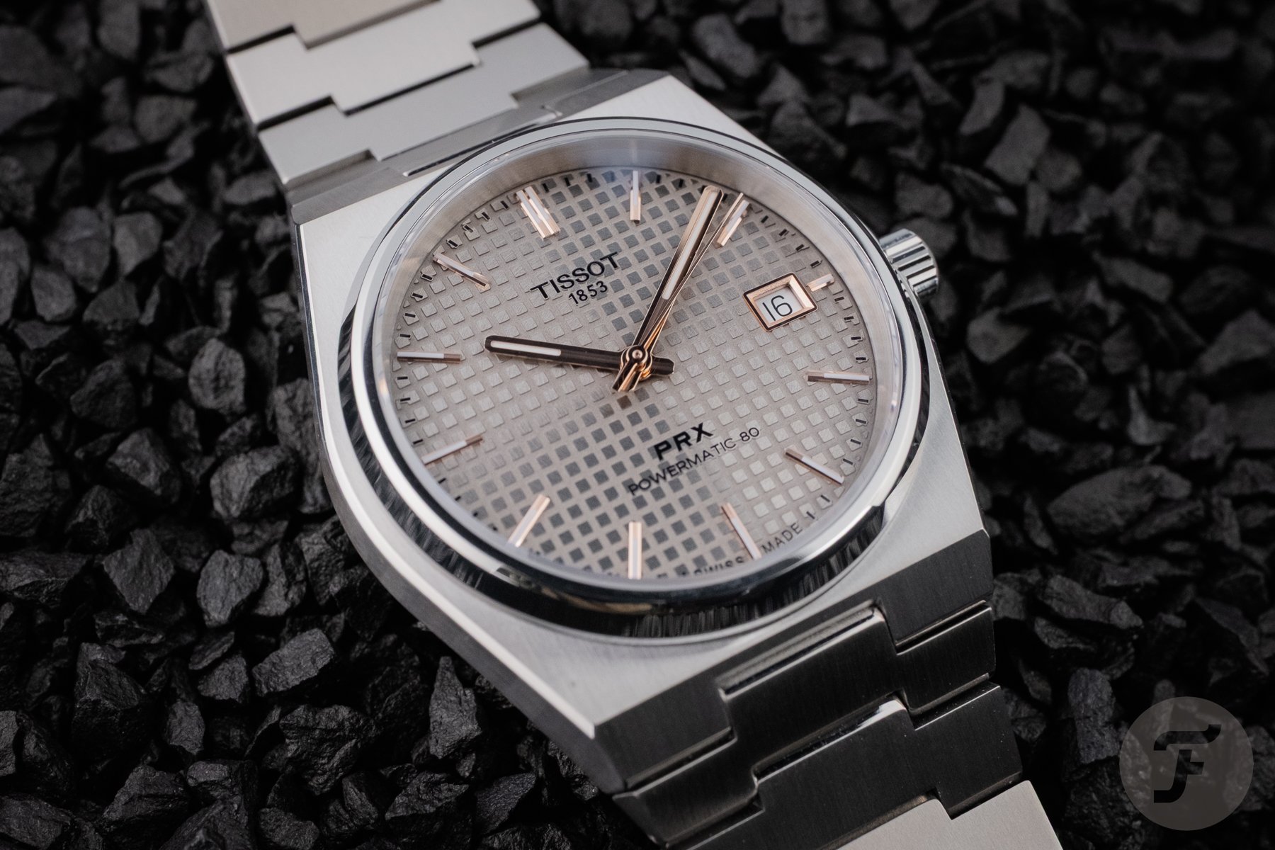 Tissot PRX Titanium 38mm on black pebbles, up close