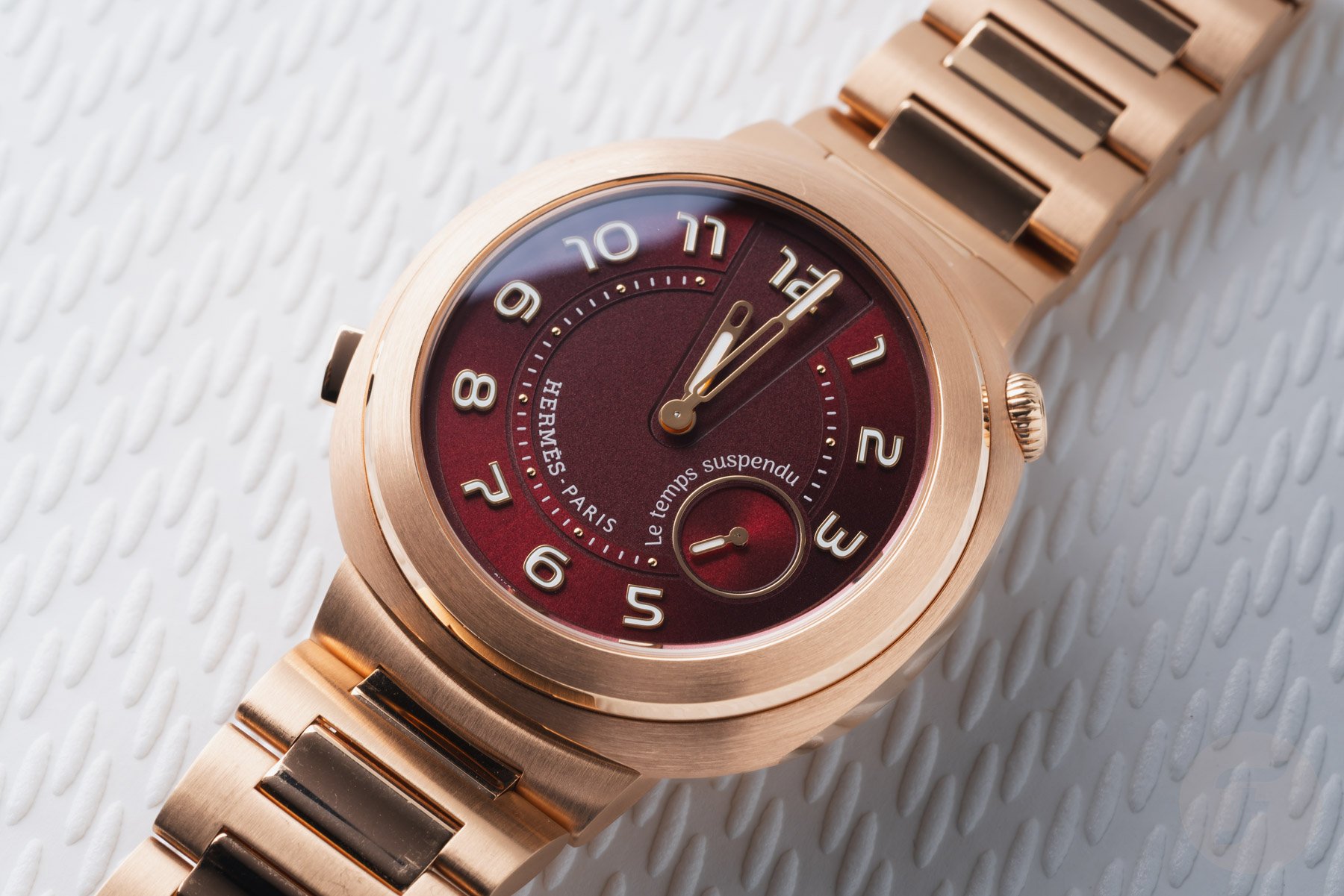 Hermès Cut Le Temps Suspendu with hands in time-out position, flat-lay