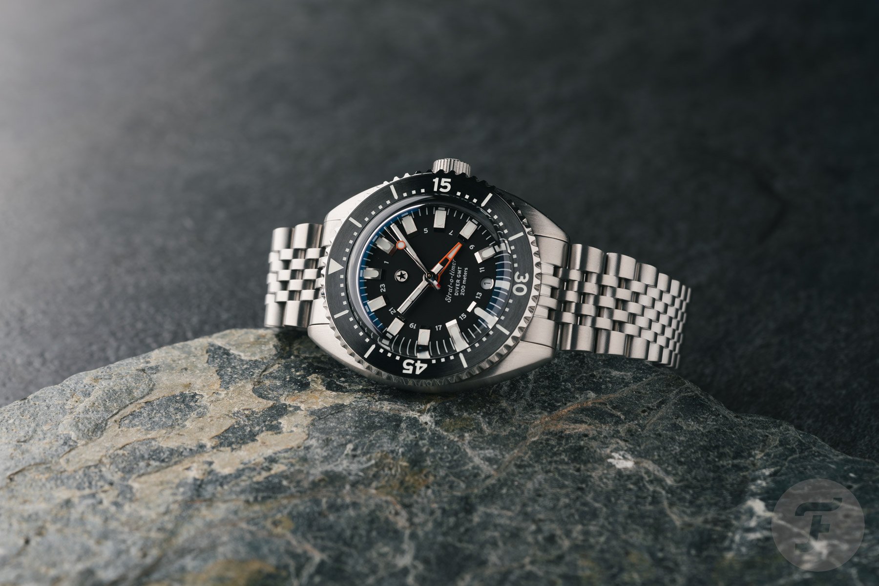 black-dial Jack Mason Strat-o-Timer Titanium Diver GMT on side, crown up, on rock