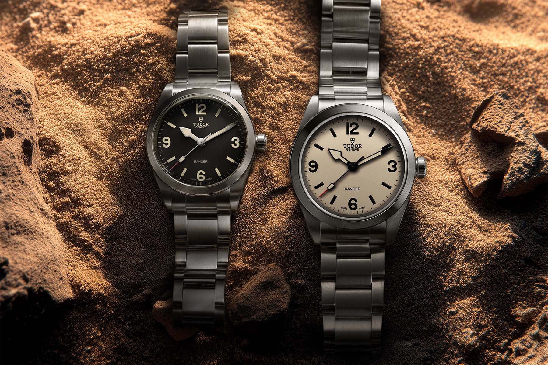 black-dial 36mm Tudor Ranger and 39mm beige-dial Tudor Ranger side by side, flat-lay on sand