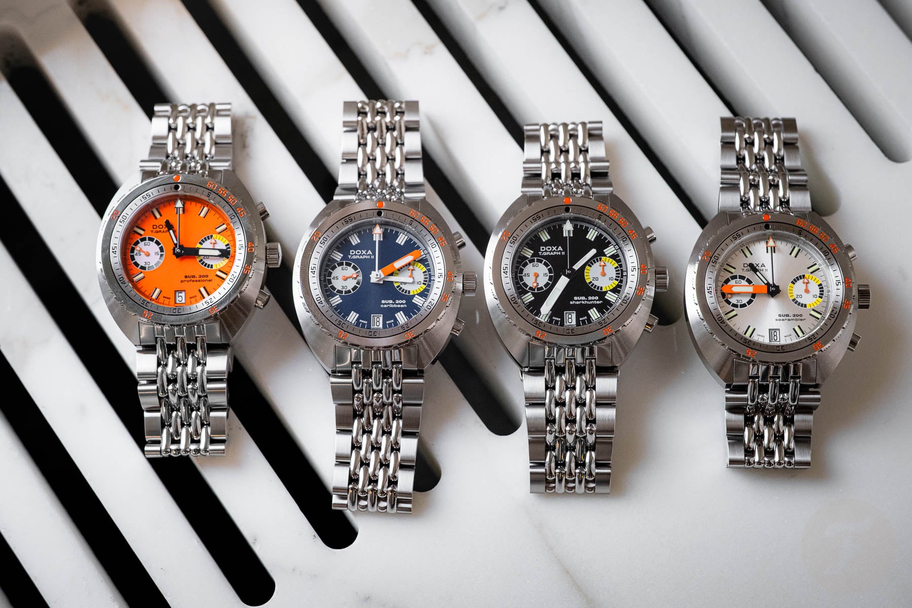 Doxa Sub 200 T.Graph II Professional, Caribbean, Sharkhunter, and Searambler side by side, flat-lay