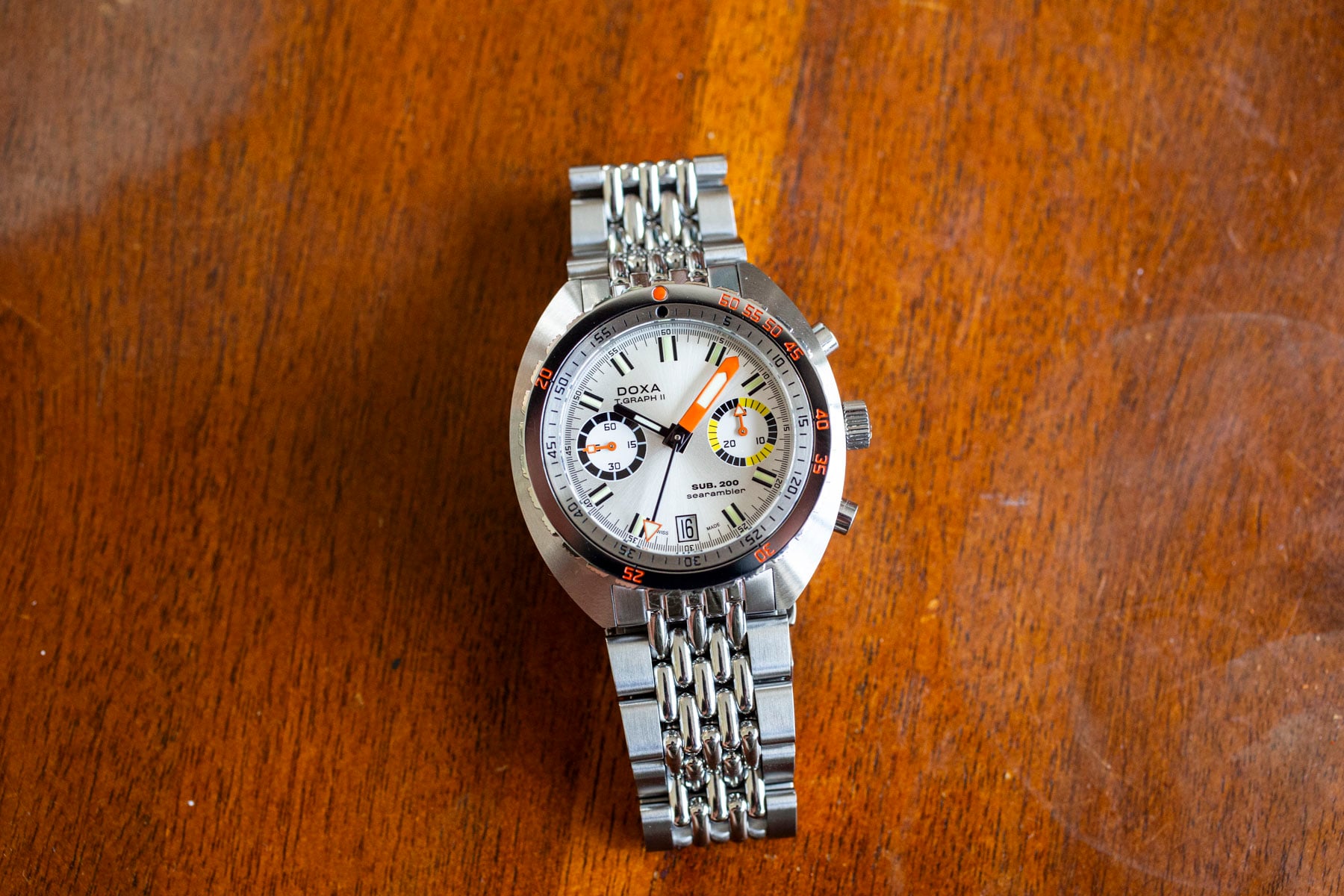 Doxa Sub 200 T.Graph II Searambler on beads-of-rice bracelet, flat-lay on wooden table
