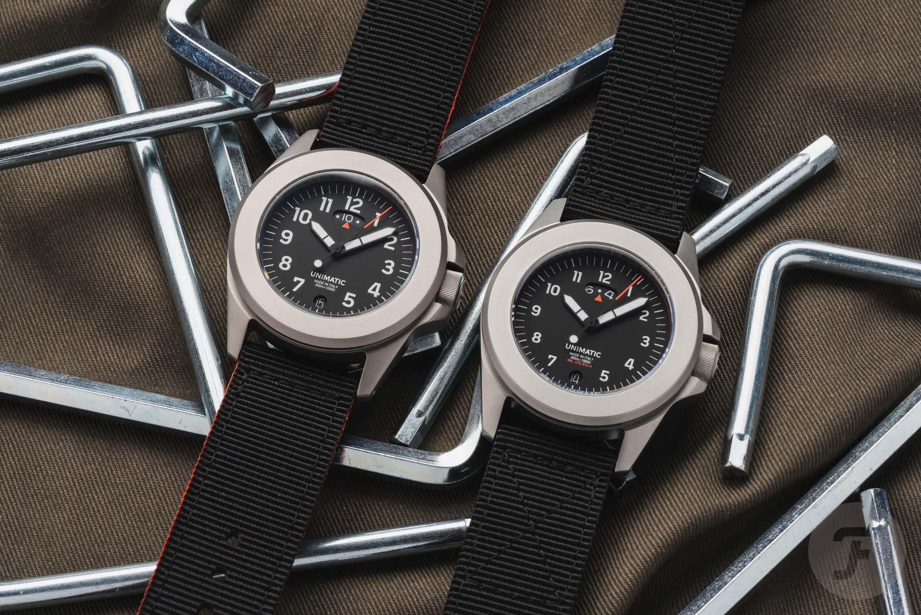 titanium Unimatic Modello Quattro UT4-U-TI-GMT next to steel UT4-GMT, flat-lay on wrenches