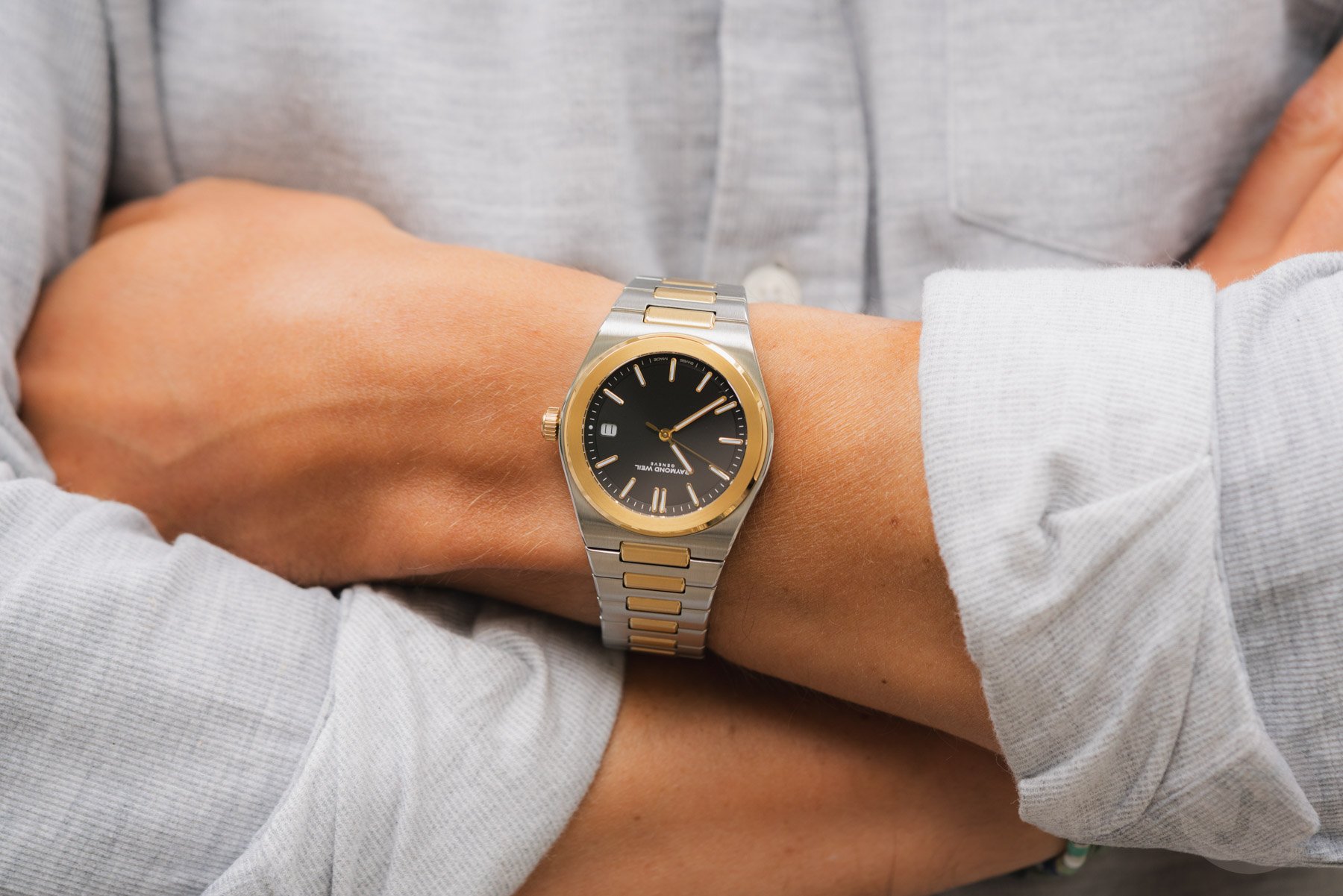 black-dial two-tone Raymond Weil A.R.T. on wrist, arms crossed