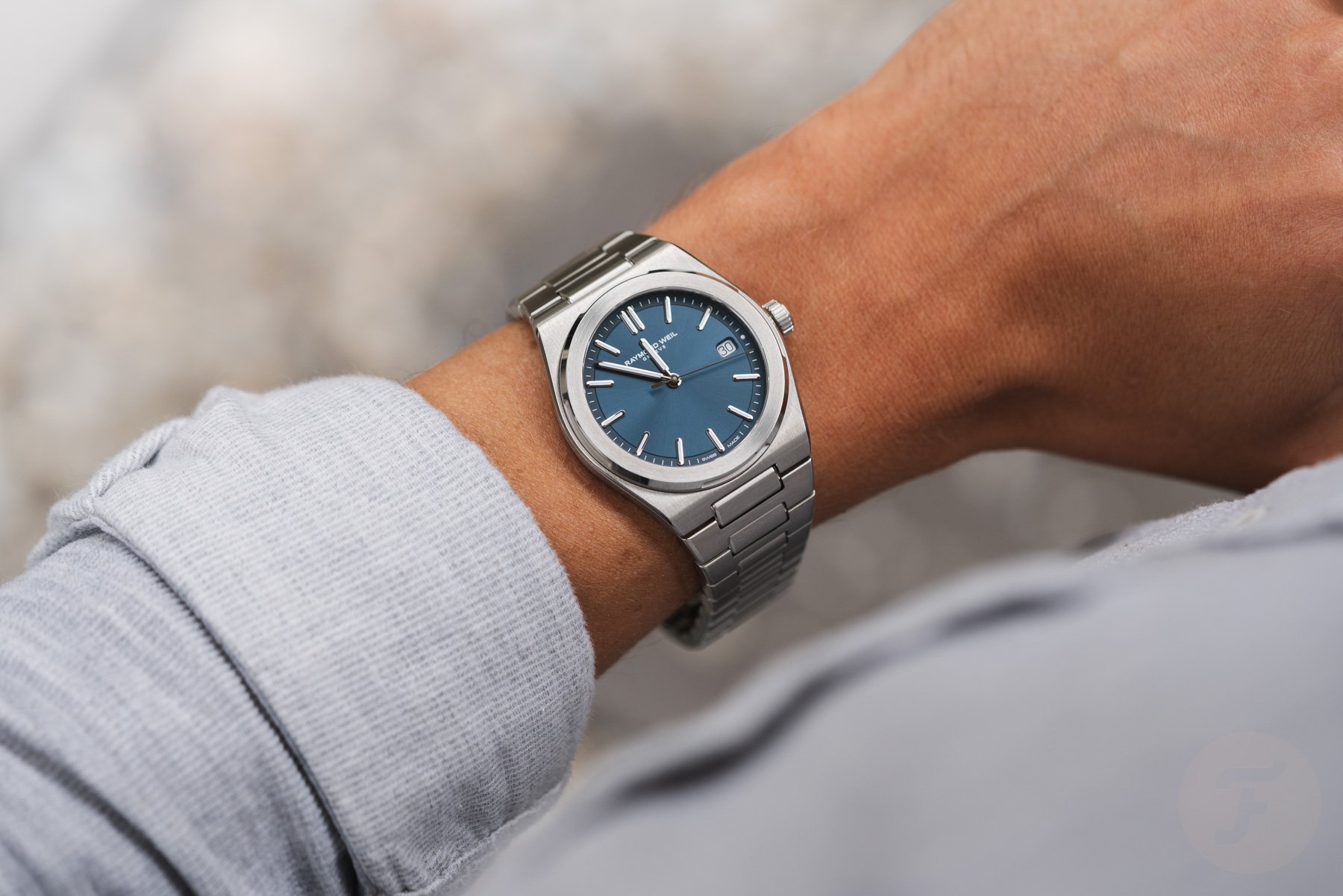 blue-dial steel Raymond Weil A.R.T. on wrist, over-shoulder shot