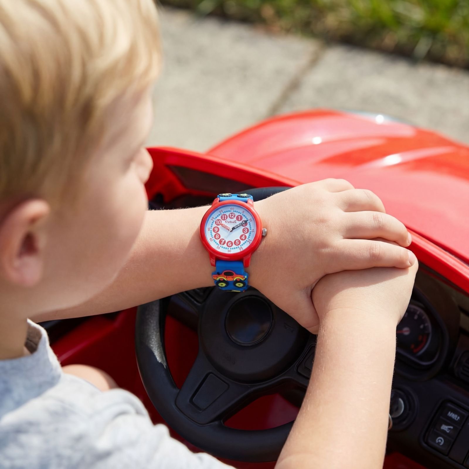 Boy wearing the Mc Onsen Cybex Big Cars watch while inside toy car