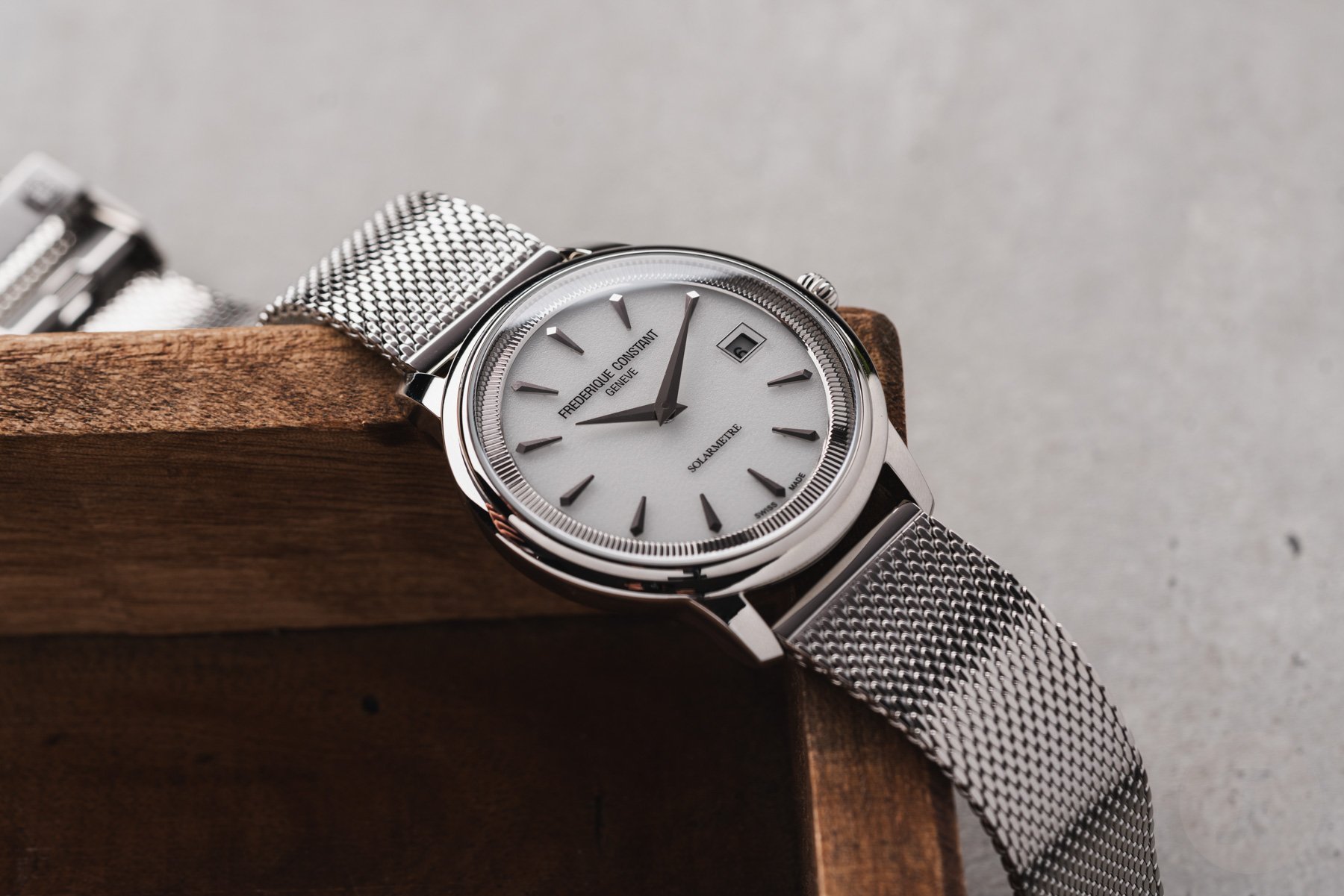white-dial Frederique Constant Moneta Solarmetre with Milanese mesh bracelet draped over edge of tray