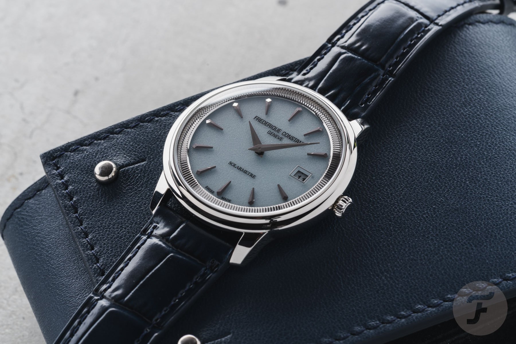 blue-dial Frederique Constant Moneta Solarmetre flat-lay on blue watch pouch