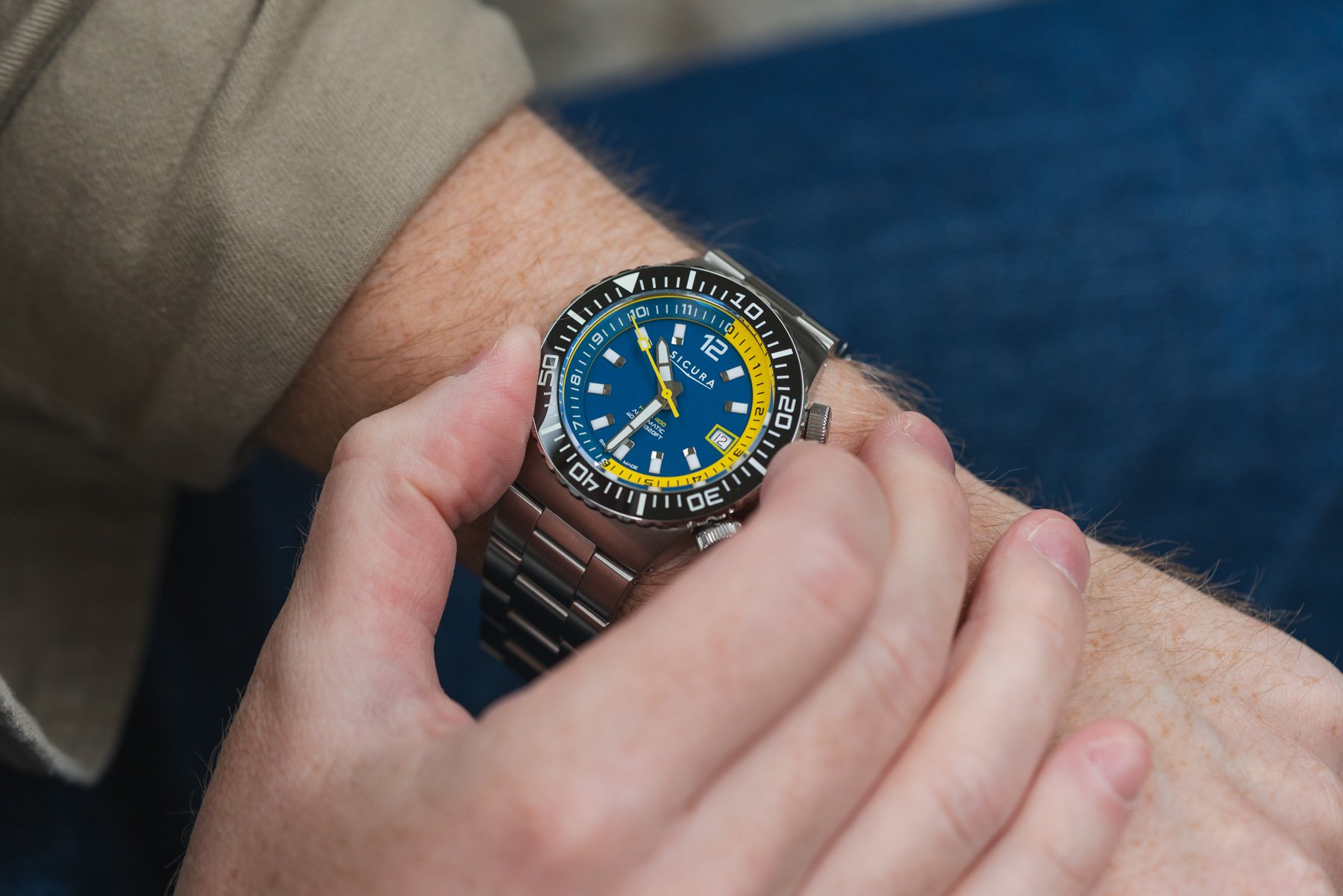 blue-dial Sicura Hexa 400 on wrist, fingers on bezel