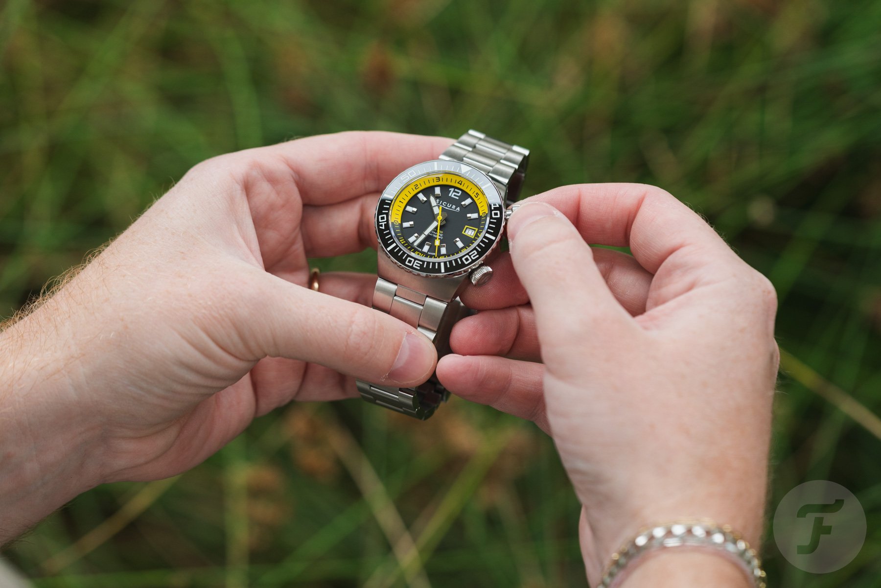 black-dial Sicura Hexa 400 in hand, fingers on top crown