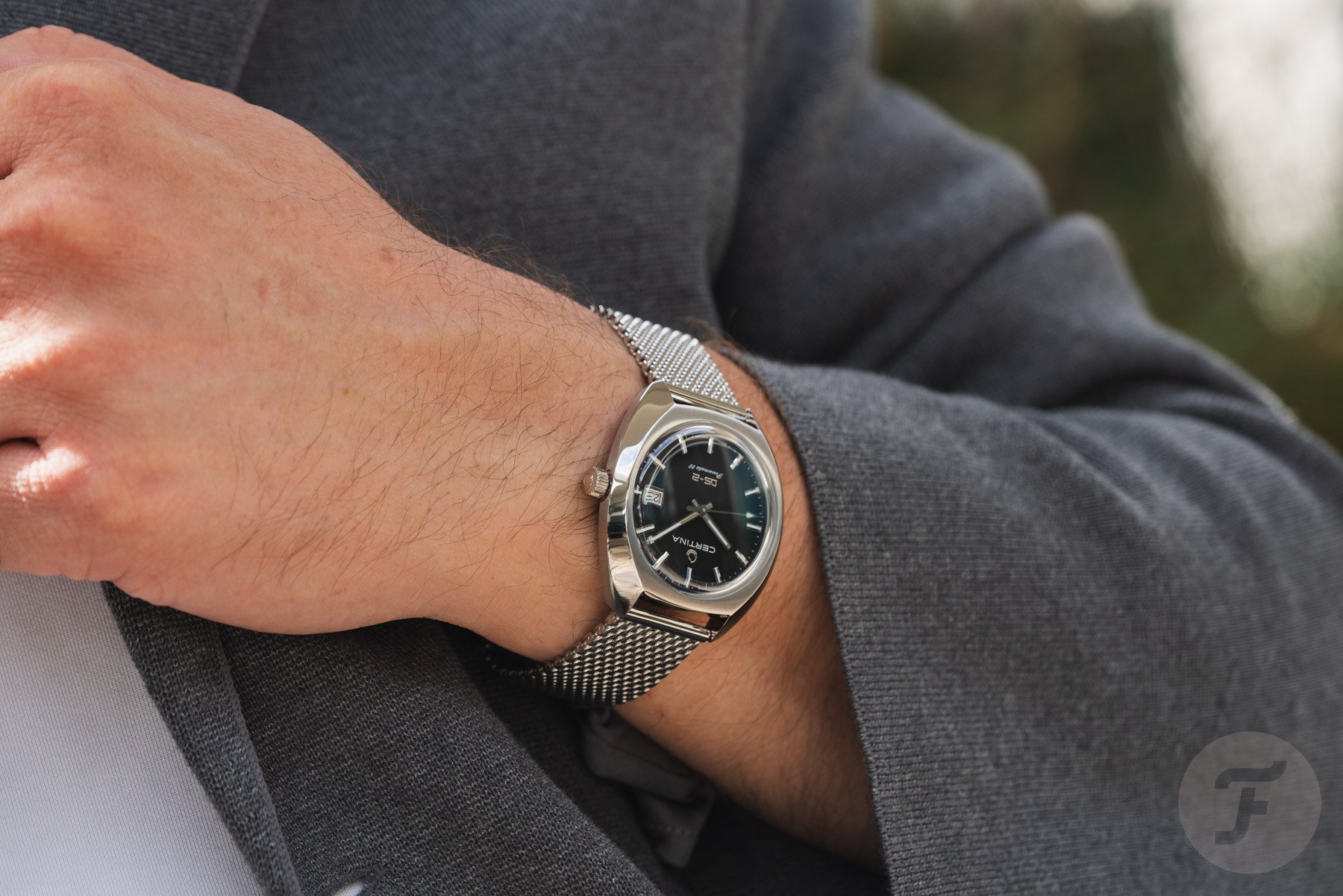 black-dial Certina DS-2 Powermatic 80 on wrist, hand on lapel