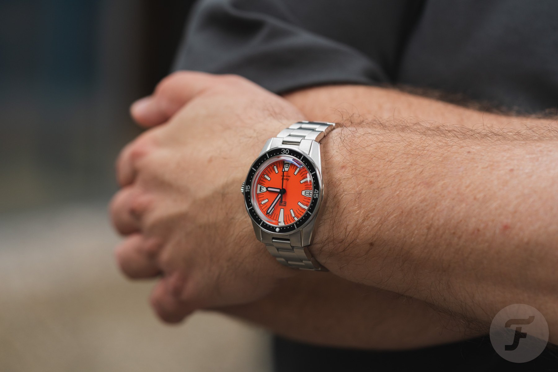orange-dial HTD Aquatìc SpaceBoy on wrist, arms crossed