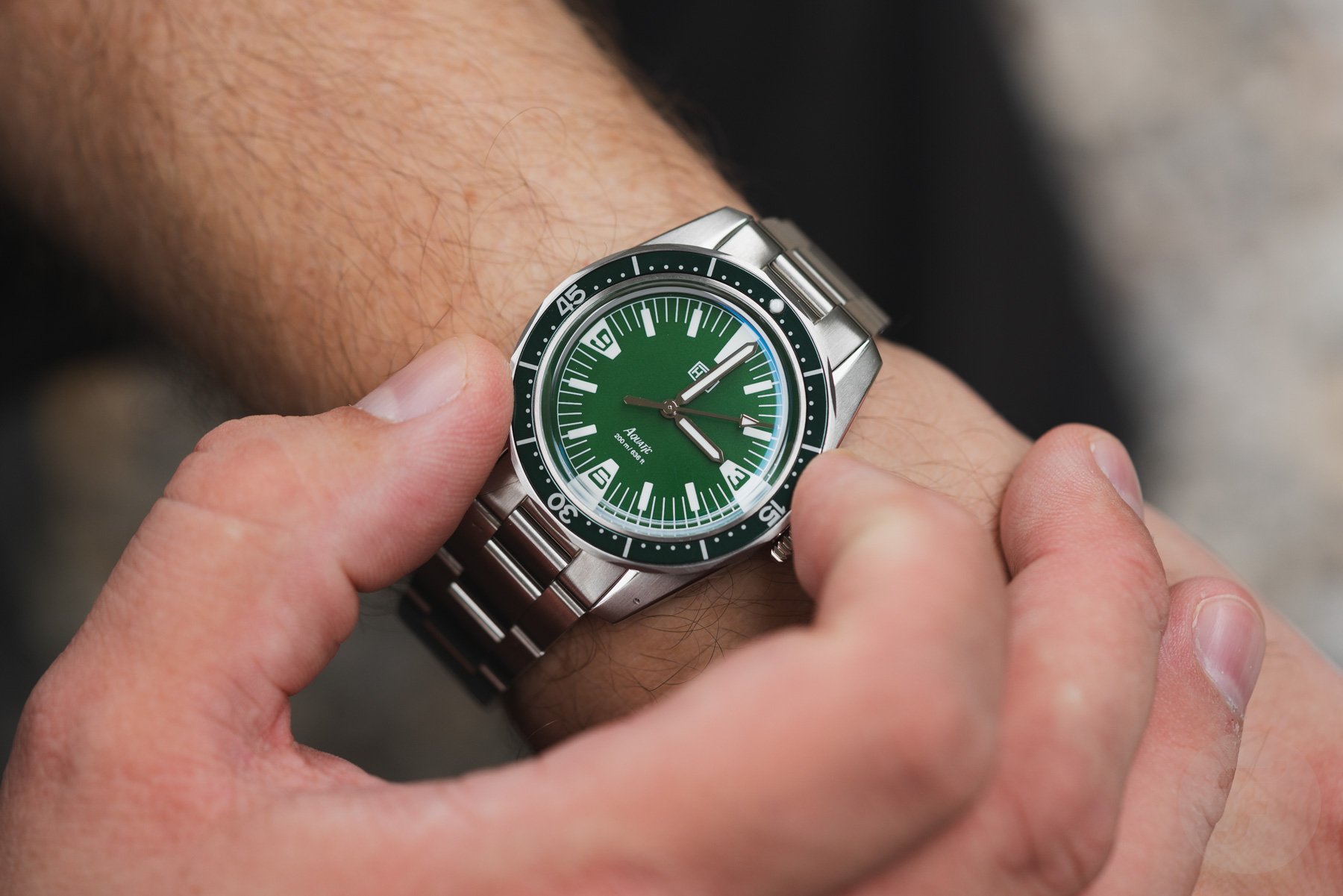 green-dial HTD Aquatìc SpaceBoy on wrist, fingers on bezel