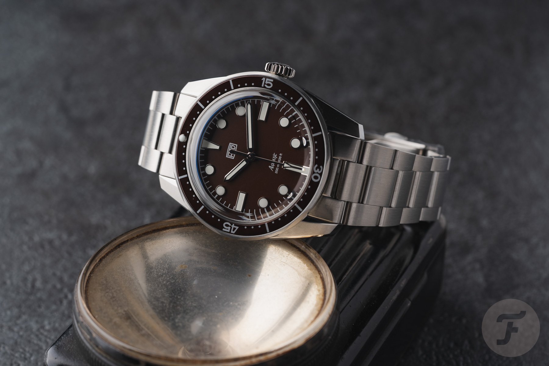 brown-dial HTD Aquatìc Bicchierini on its side, crown up, on top of light