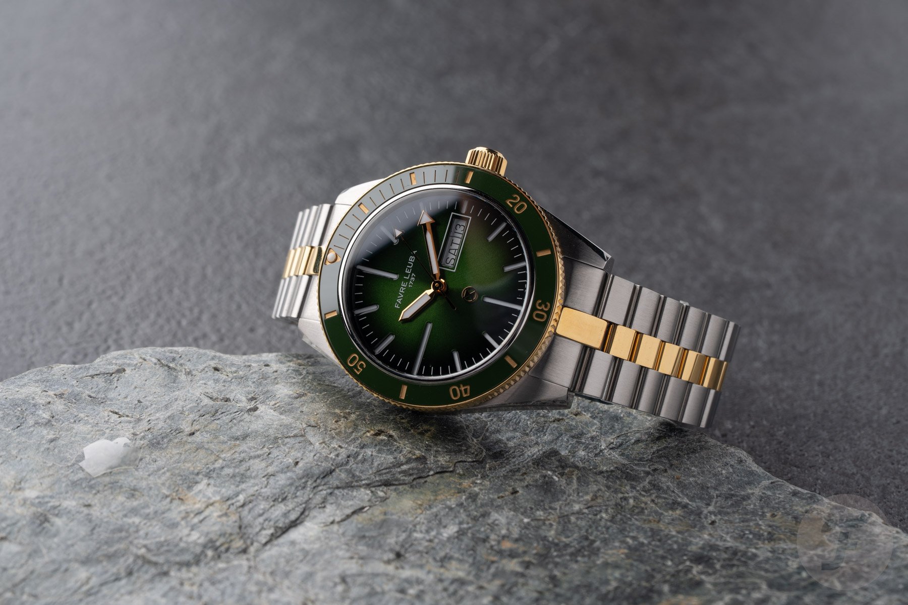 green-dial two-tone Favre Leuba Deep Raider Day Date on its side on top of rock, crown up