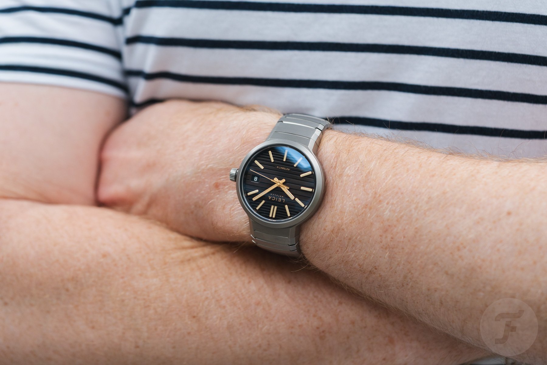 Leica ZM 11 Titanium Coffee Black with bracelet on wrist, arms crossed