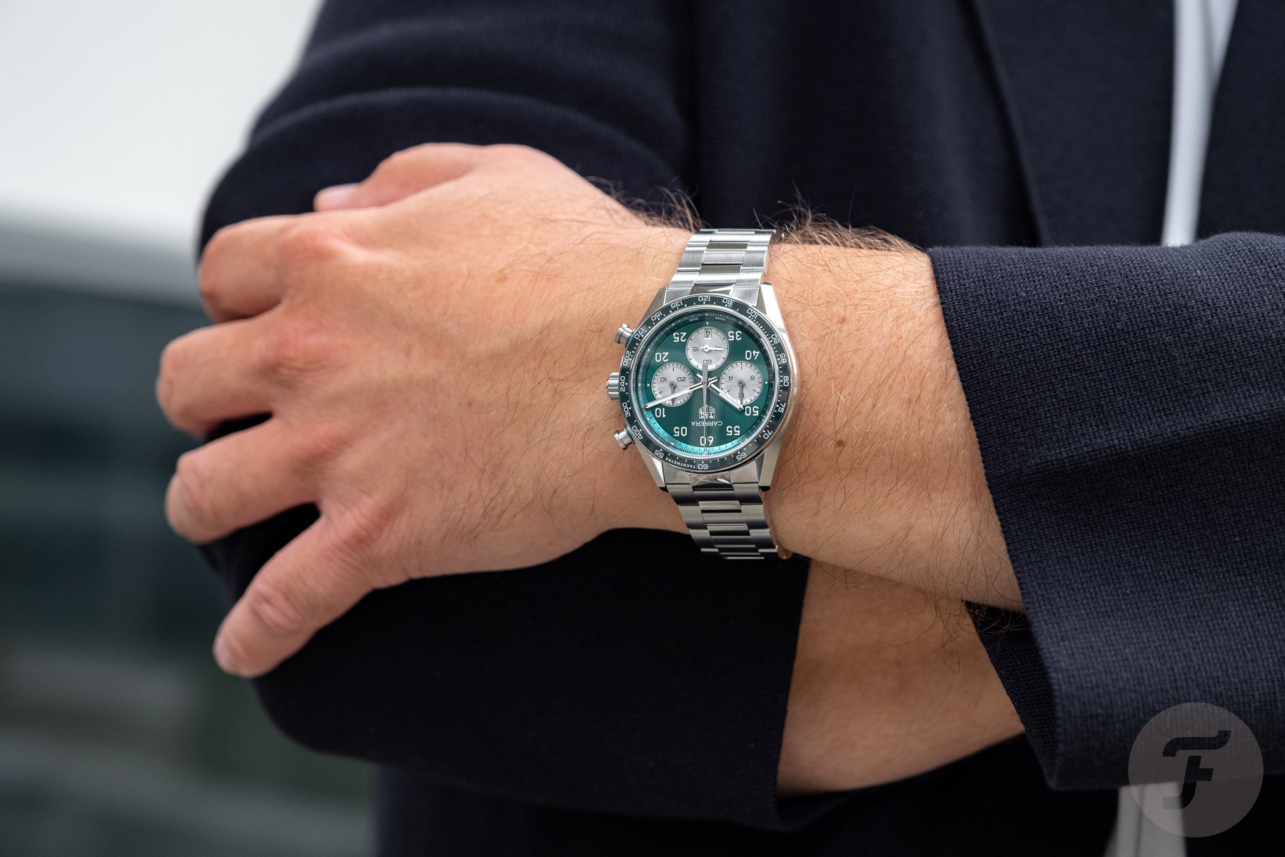 green-dial TAG Heuer Carrera Chronograph Sport on wrist, arms crossed