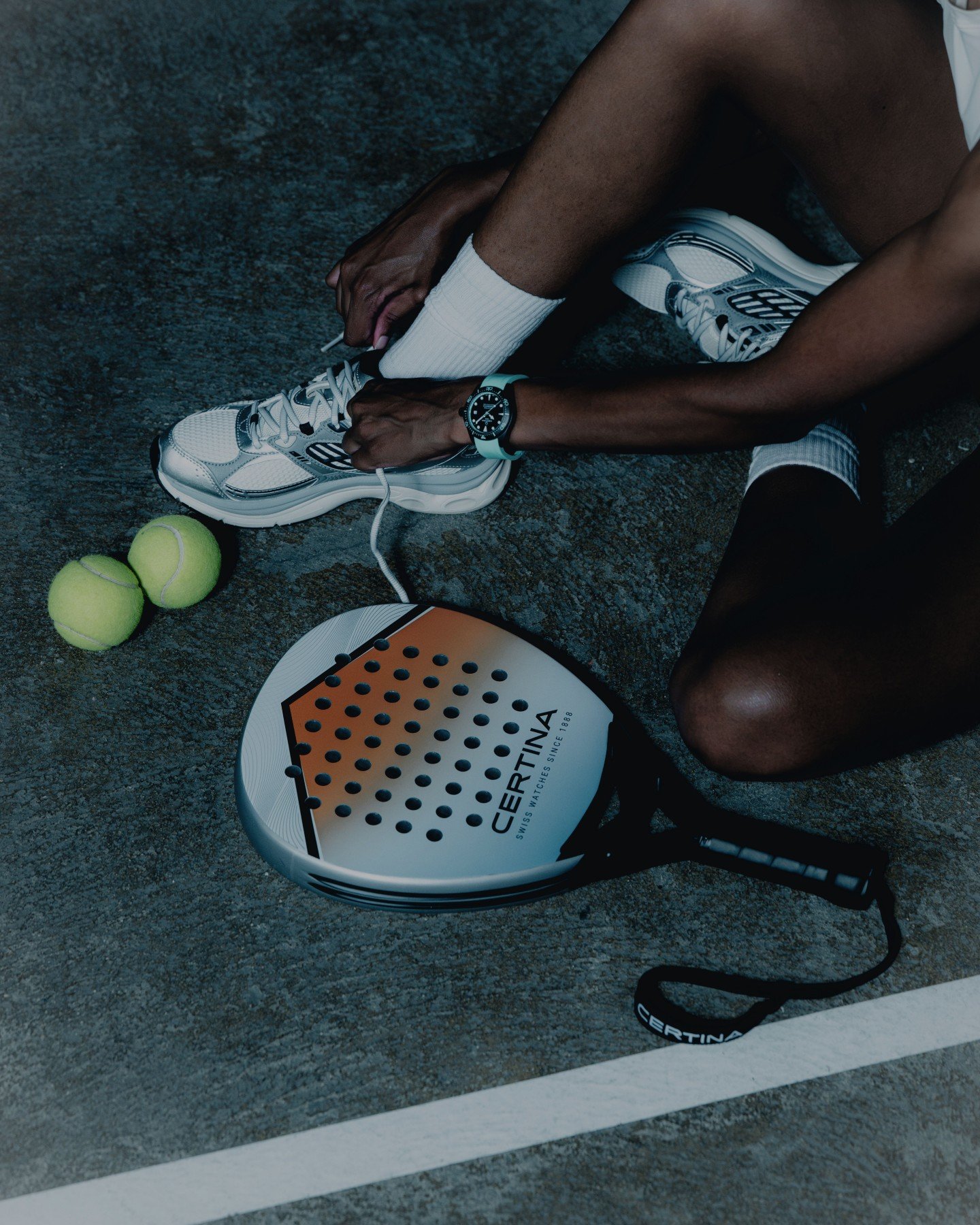 man tying shoe while wearing Certina DS Action Diver 38mm ref. C048.807.33.051.01 on padel court