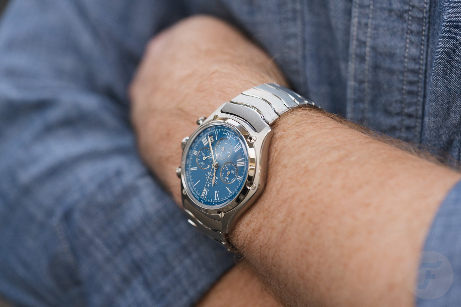 steel blue-dial Ebel Sport Classic Chronograph LE on wrist, arms crossed