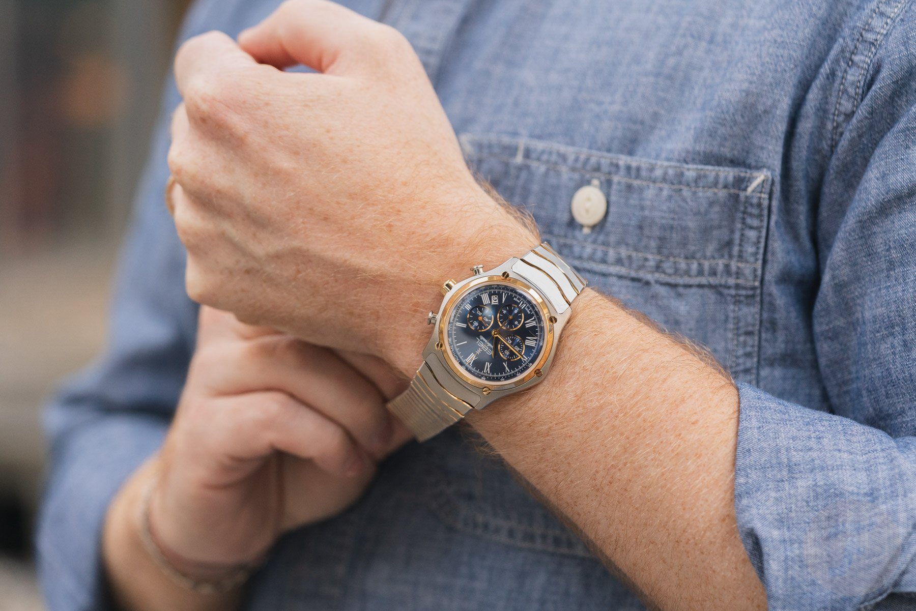 steel-and-gold blue-dial Ebel Sport Classic Chronograph LE on wrist, holding bracelet